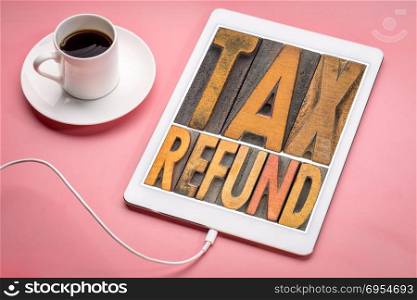 tax refund - word abstract in vintage letterpress printing blocks on a digital tablet with a cup of coffee