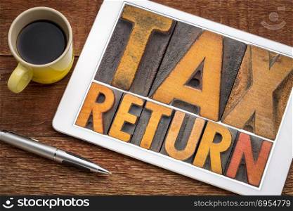 tax return - word abstract in vintage letterpress printing blocks on a digital tablet with a cup of coffee