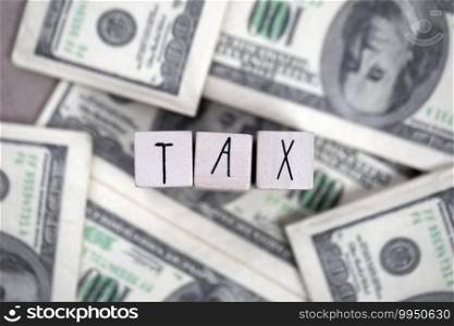 Tax text with hundred dollar bills background, business, financial and tax time concept close up. Tax text with hundred dollar bills background, business, financial and tax time concept