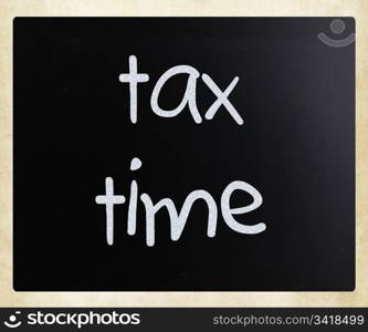 ""Tax time" handwritten with white chalk on a blackboard"