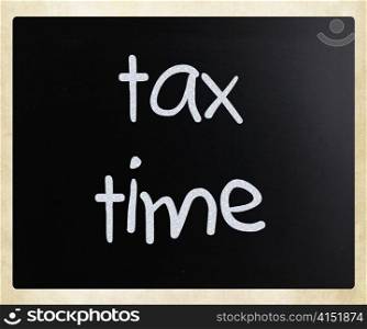 ""Tax time" handwritten with white chalk on a blackboard"