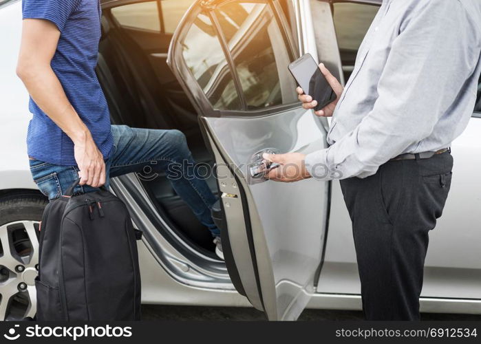 Taxi driver greeting his passengers with their luggage on the sidewalk of a modern city