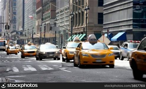 Taxis and other vehicles driving down a typical city street in New York