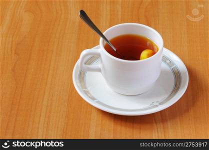 Tea. A white cup with tea and a lemon on a table