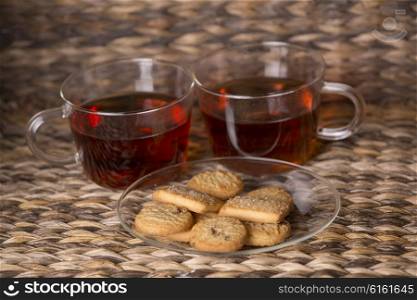 Tea and cookies on wooden table in front of a wooden background