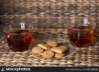 Tea and cookies on wooden table in front of a wooden background