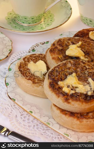 Tea and toasted crumpets with lashings of melting butter for Breakfast. A crumpet is a savoury griddle cake made from flour and yeast. It is eaten mainly in the United Kingdom and other nations of the Commonwealth.