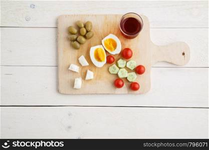 tea and Turkish,Mediterranean Breakfast of olives,eggs,cheese,tomatoes and cucumbers on a light wooden tray on a white natural background . the view from the top