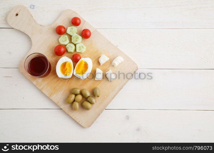 tea and Turkish,Mediterranean Breakfast of olives,eggs,cheese,tomatoes and cucumbers on a light wooden tray on a white natural background . the view from the top