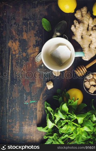 Tea composition on rustic background: tea, mint, lemon, ginger. Flat lay top view