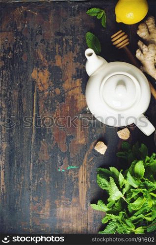 Tea composition on rustic background: tea, mint, lemon, ginger. Flat lay top view