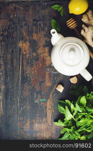 Tea composition on rustic background: tea, mint, lemon, ginger. Flat lay top view