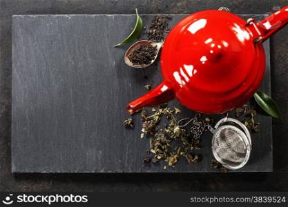 Tea composition with red teapot on dark background