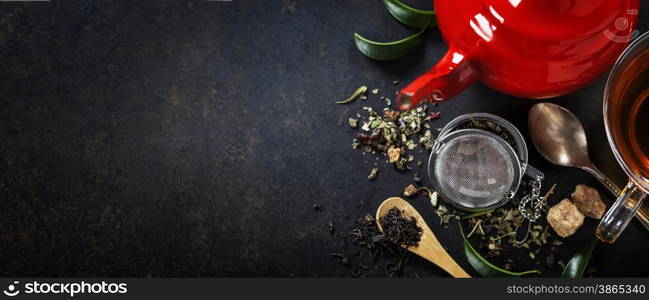 Tea composition with red teapot on dark background