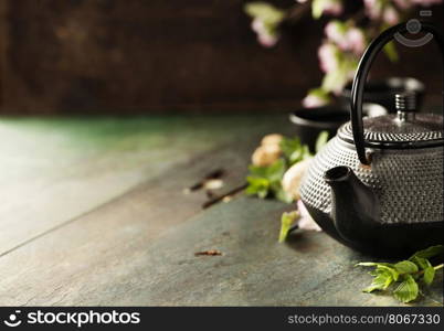 Tea concept, cups with tea and traditional teapot decorated with blooming spring tree branch