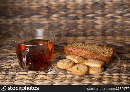 Tea, cookies and cake on wooden table in front of a wooden background