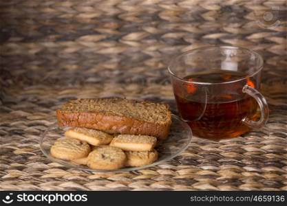 Tea, cookies and cake on wooden table in front of a wooden background