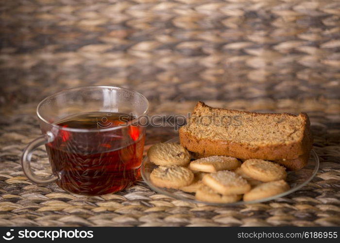 Tea, cookies and cake on wooden table in front of a wooden background