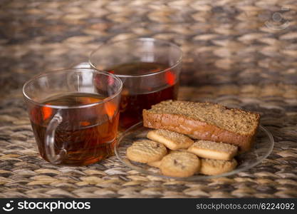 Tea, cookies and cake on wooden table in front of a wooden background