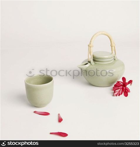 Tea cup and a tea kettle with flower petals