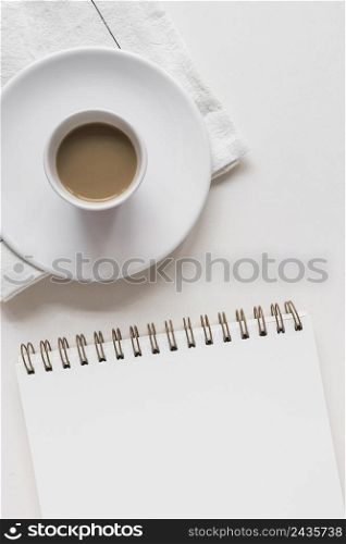 tea cup saucer napkin with spiral notepad against white background