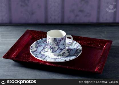 Tea cup victorian style on red indian tray, purple wallpaper background