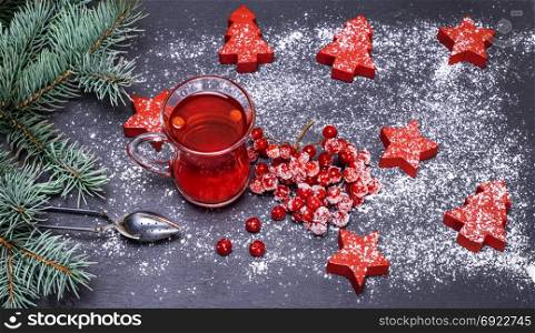 tea from berries of a viburnum in a transparent mug on a black background and festive decor