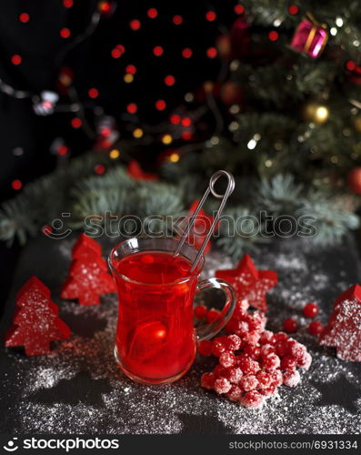 tea from fresh red viburnum in a transparent glass on a black background