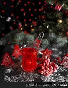 tea from fresh red viburnum in a transparent glass on a black background