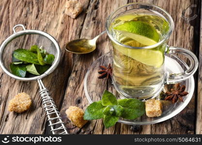 Tea.Green tea with lime, mint and sugar cubes. Tea brewed with lime and mint on wooden background
