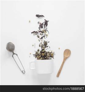tea herbs falling from cup with strainer spoon white backdrop. Resolution and high quality beautiful photo. tea herbs falling from cup with strainer spoon white backdrop. High quality and resolution beautiful photo concept