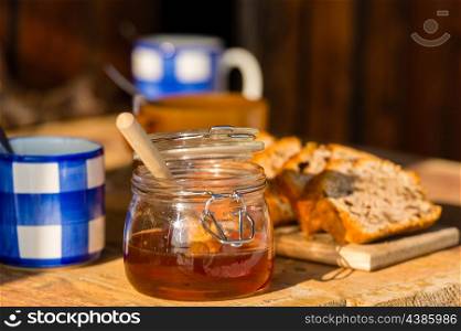 Tea, honey and fruit bread on wooden table sunny outdoor