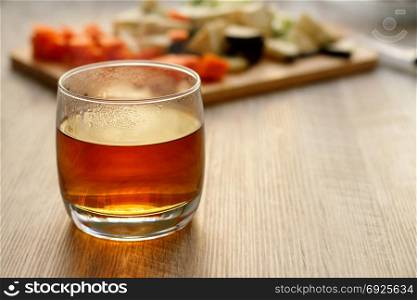Tea in a glass on a wooden table. Hot tea in a glass, in backlight, against the background of products.