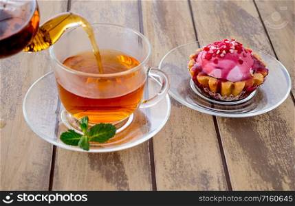 Tea in glass cup and mint on wooden background. Cup with tea on wooden background.