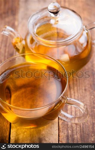 Tea in glass cup with glass teapot on wooden table still life