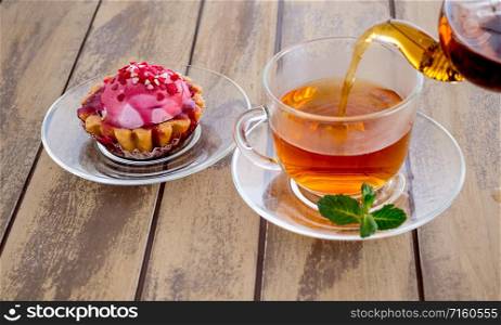 Tea in glass cup with lemon and mint on wooden background. Tea with fresh leaves mint and lemon slice