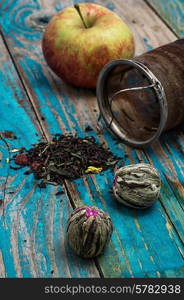 tea leaves and red apple on wooden background.The image is tinted in vintage style. tea leaves and red apple on wooden background