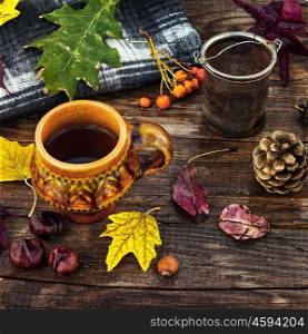 Tea party in October. Cup of tea on the table strewn with autumn leaves and warm blanket