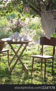 tea party in the garden. on the table is a vase of flowers, pie with cherry and cup of tea 