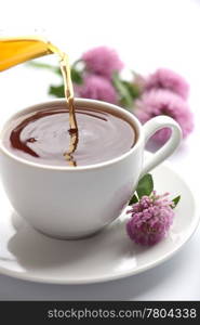 tea pouring into white cup isolated