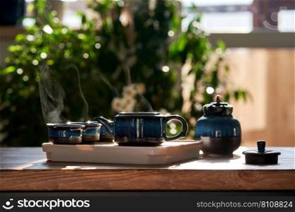 Tea set of deep blue color on a background of greenery in the rays of the contour sun. Preparation for the tea ceremony.. Tea set of deep blue color on a background of greenery.