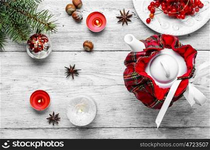 tea with cranberry. Kettle in stylish tea warmer Christmas background