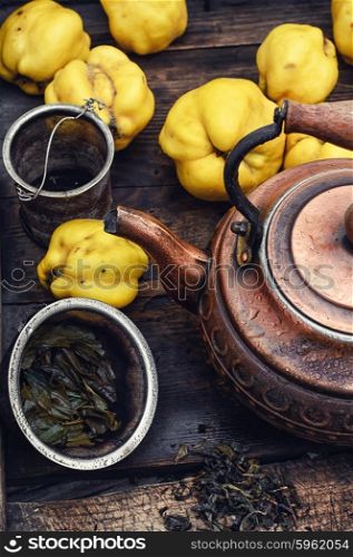Tea with fresh quince. Obsolete wooden box with a stylish copper kettle and fruit quince
