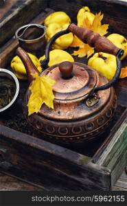 Tea with fresh quince. Obsolete wooden box with a stylish copper kettle and fruit quince