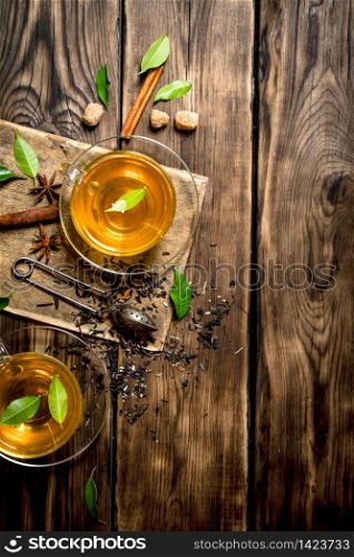 Tea with infuser spoon, cinnamon and brown sugar. On wooden background.. Tea with infuser spoon, cinnamon and brown sugar.