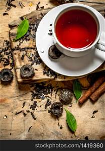 Tea with leaves and cinnamon. On wooden background.. Tea with leaves and cinnamon.