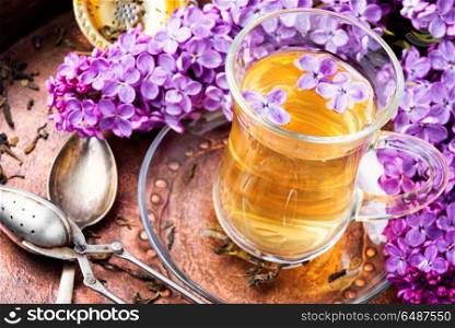 Tea with lilac flavor. Cup of fragrant spring tea and a branch of blossoming spring lilac.Green tea