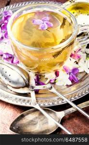 Tea with lilac flavor. Cup of fragrant spring tea and a branch of blossoming spring lilac.Green tea