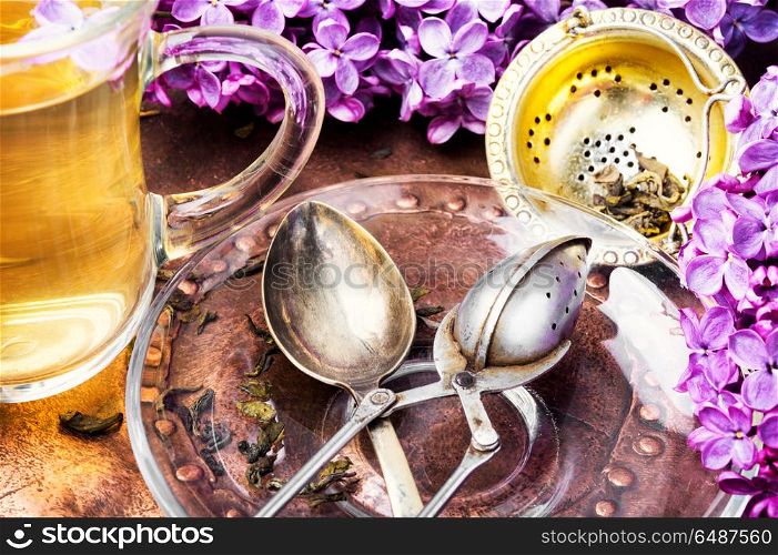Tea with lilac flavor. Cup of fragrant spring tea and a branch of blossoming spring lilac.Herbal tea