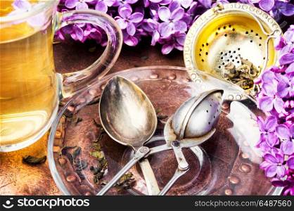 Tea with lilac flavor. Cup of fragrant spring tea and a branch of blossoming spring lilac.Herbal tea
